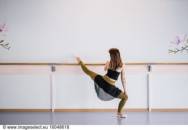 Ballerina stretching leg in dance studio