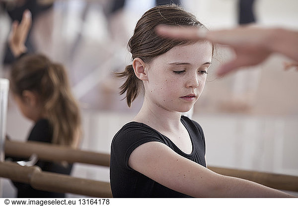 Ballet school girls practicing ballet position at the barre
