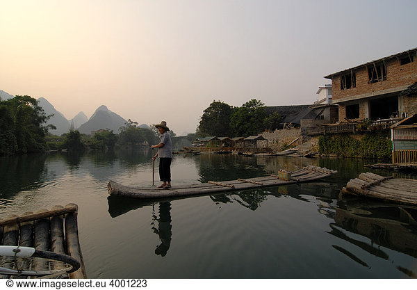 Bambusfloß mit altem chinesischem Mann mit Strohhut auf dem Yulong Fluss in der Karstfelsenlandschaft bei Yangshuo Guilin Guangxi China Asien