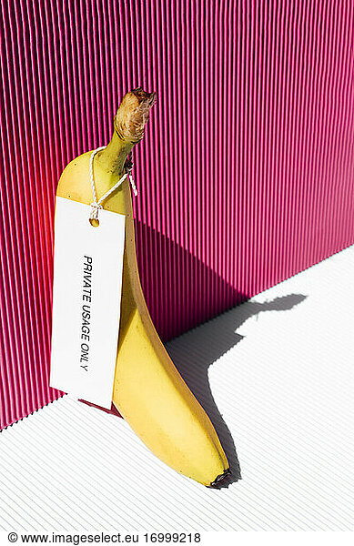 Banana with tag private usage only against pink background