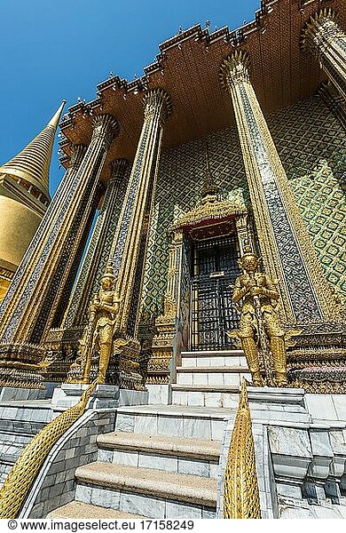 Bangkok  Thailand. Blick auf die goldenen Riesenstatuen  die das massive Tor zum Phra Mondop im Wat Phra Kaew Tempel in Bangkok  Thailand  bewachen.