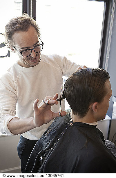Barber cutting man's hair with scissors in hair salon