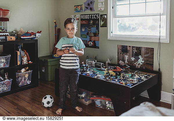 Barefoot boy in striped shirt with LEGOâ€™s  soccer ball & bins of toys