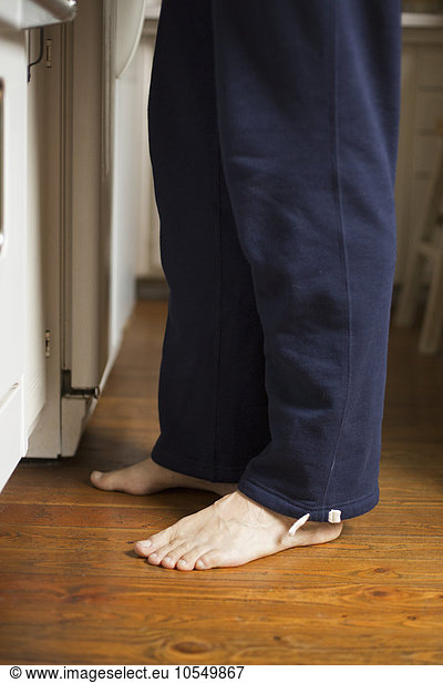 Barefoot man standing in a kitchen.