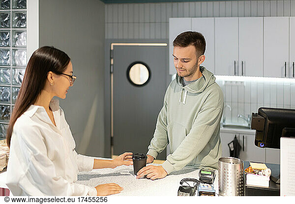 Barista serving coffee to go to client