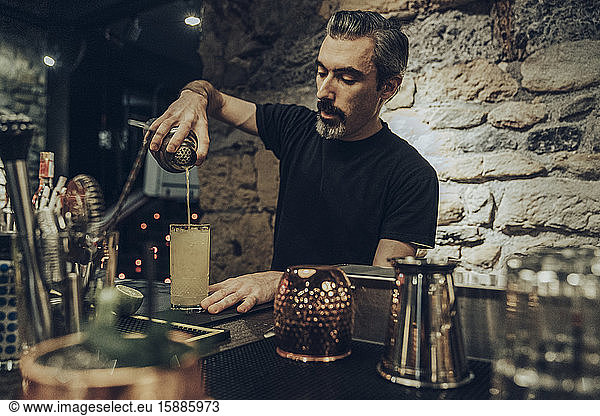 Barkeeper schenkt Cocktail in ein Glas ein