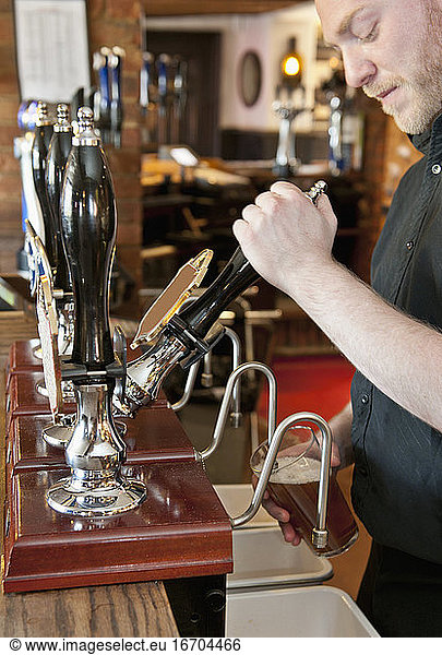 Barkeeper zapft Bier in einem britischen Pub