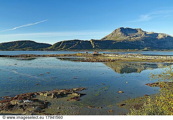 Barren mountains reflected in the shallow waters of a fjord arm  small cabin  Nordland  RV 17  Kystriksveien  Norway  Europe