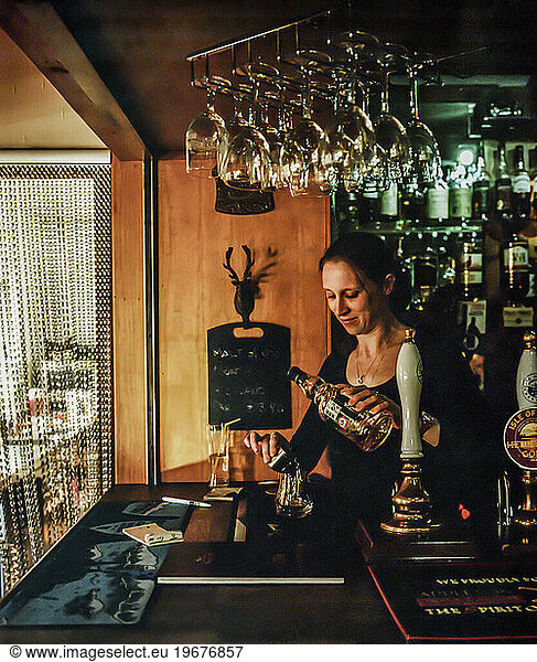 Bartender pouring scotch at local bar in Broadford  Isle of Skye  Scotland  UK