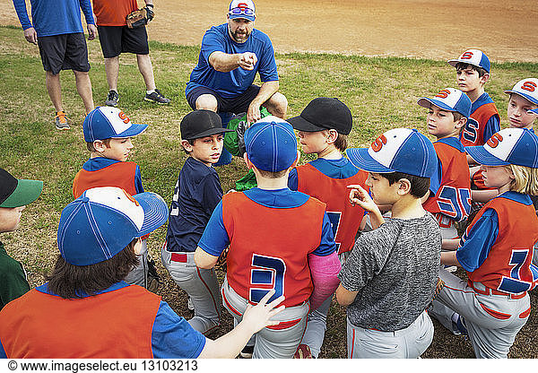 Baseball coach instructing boys on field