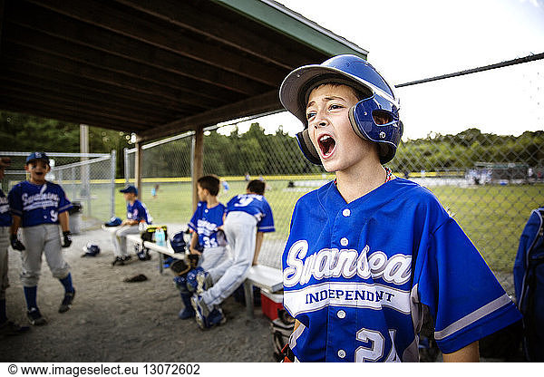 Baseball player shouting while standing in dugout