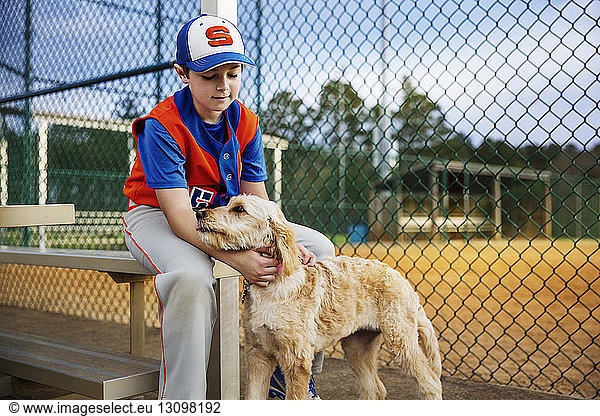 Baseball player stroking dog on field