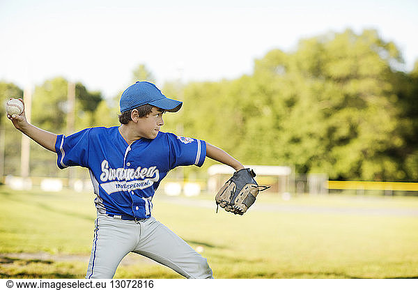 Baseball player throwing ball against sky