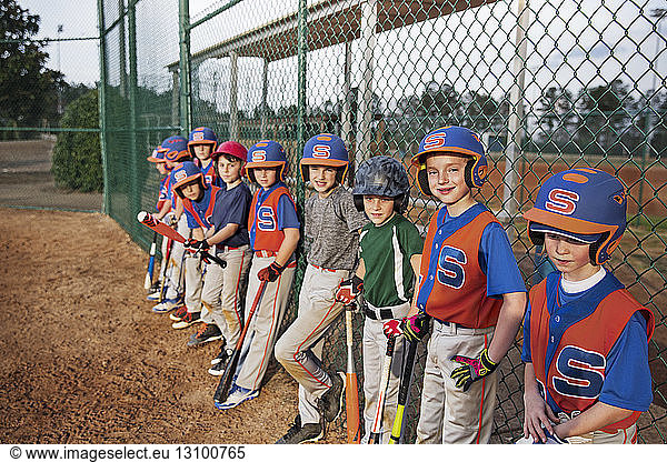 Baseball team standing by chainlink fence on field