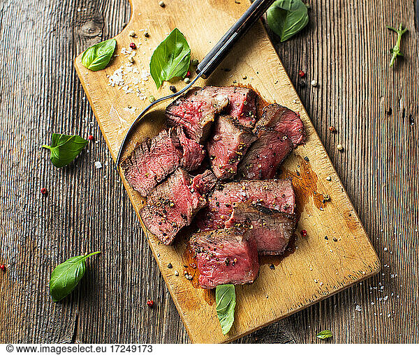 Basil  fork  peppercorns and steak lying on cutting board