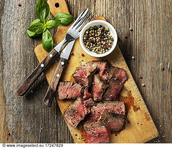 Basil  forks  peppercorns and steak lying on cutting board