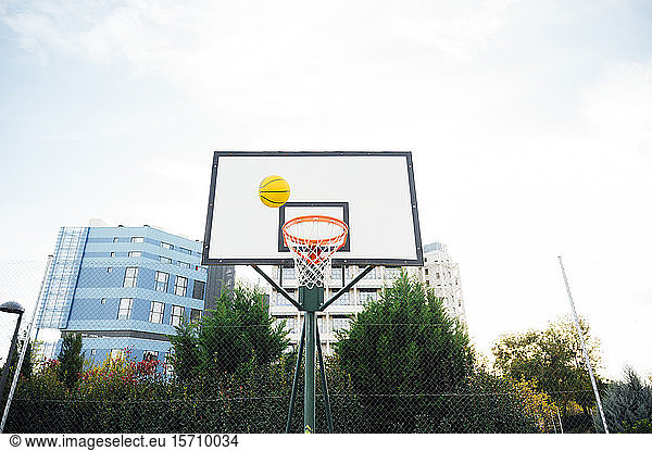 Basketball at hoop on outdoor court