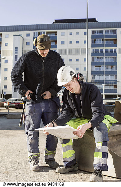 Bauarbeiter analysieren Bauplan vor Ort