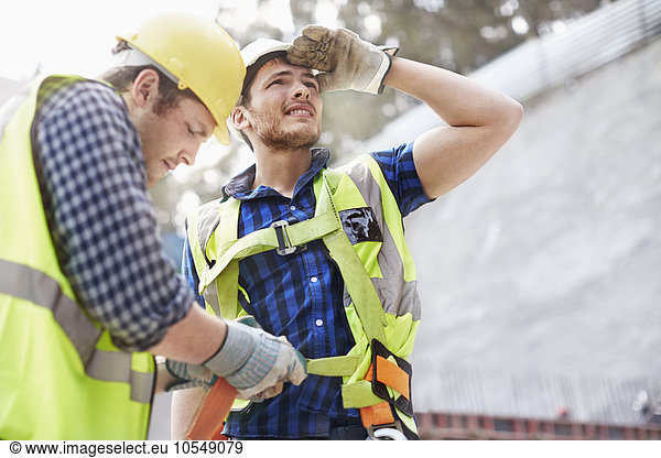 Bauarbeiter beim Befestigen von Mitarbeiter-Sicherheitsgurten