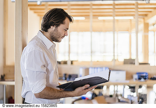 Bbusinessman looking at folder in wooden open-plan office