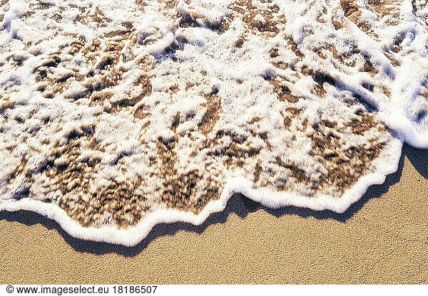 Beach sand brushed by foamy wave