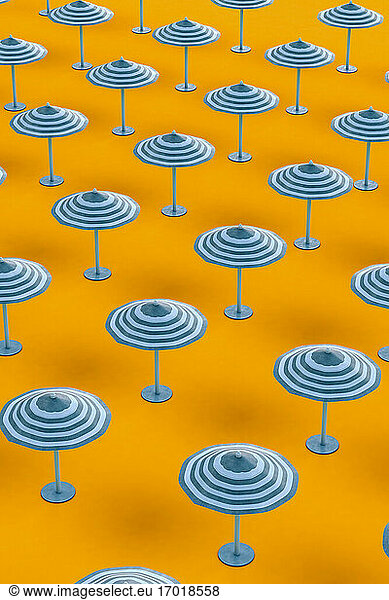 Beach umbrellas arranged in row on orange background