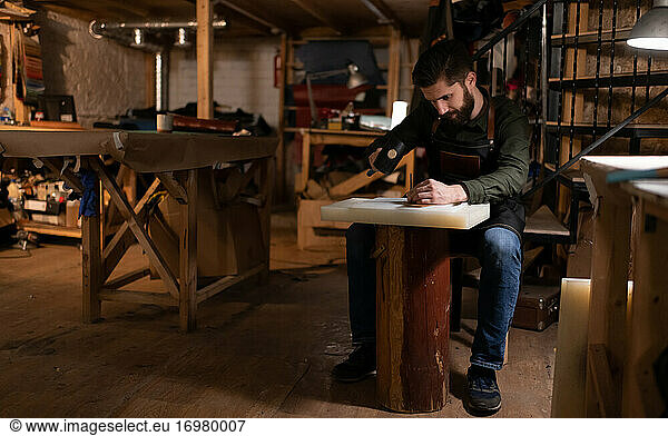 Bearded craftsman making leather handicraft