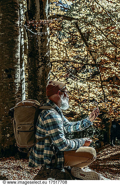 bearded man consults his manual compass on a sunset excursion