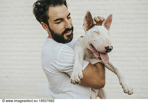 bearded man hugging white bull terrier dog