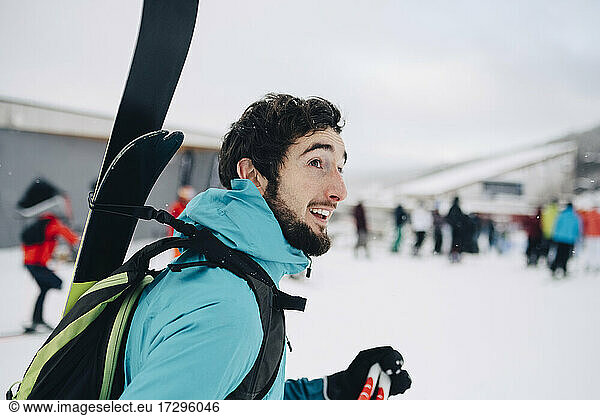 Bearded man wearing backpack while looking away at ski resort