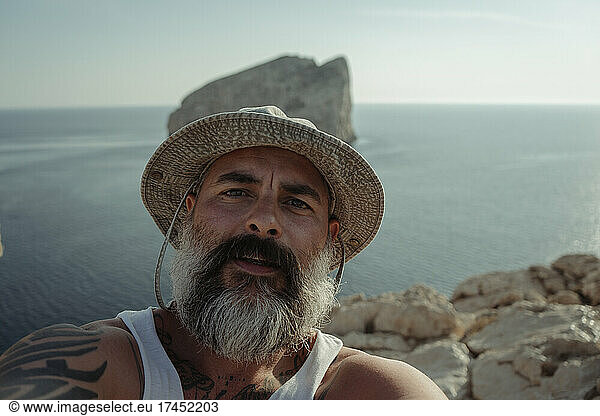 Bearded man with hat taking selfie with his camera
