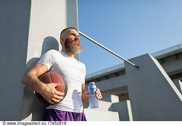 Bearded sportsman with basketball ball and water
