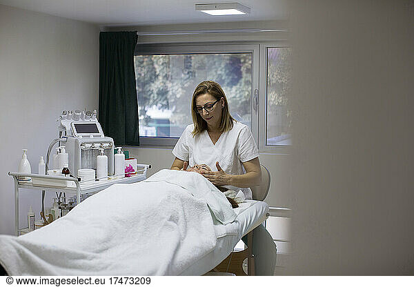 Beautician massaging face of woman in salon