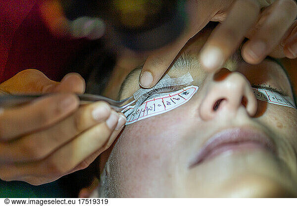 beautician placing false eyelashes to client at home