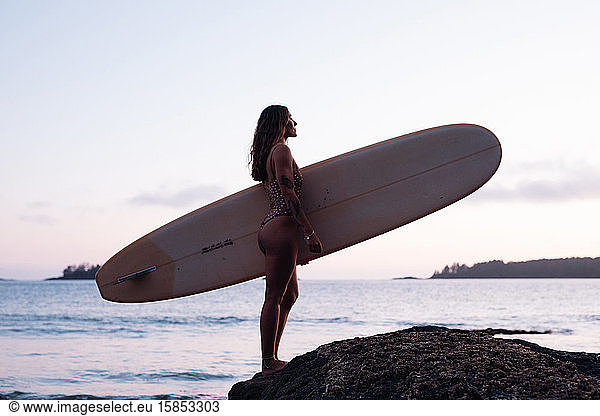 Beautiful,  fit woman with surfboard on beach in Tofino