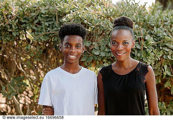 Beautiful African American mom outdoors with smiling preteen son