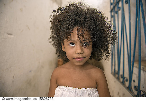 Beautiful Afro-Brazilian girl with curly hair and white dress  smiles