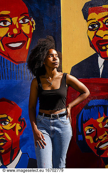 Beautiful artist in golden light displays her mural of Black heroes