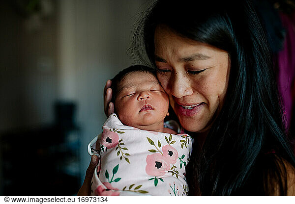 Beautiful asian mother overwhelmed with love for newborn child