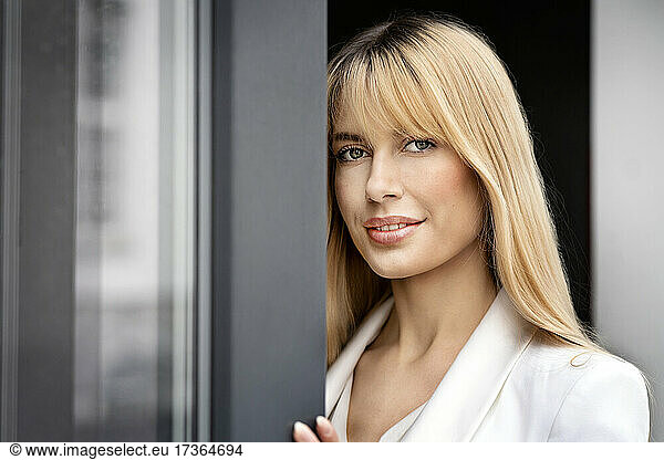 Beautiful blond businesswoman with bangs at window
