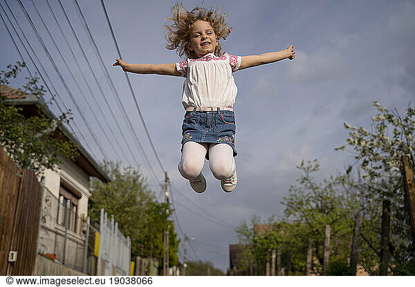 Beautiful blond girl with light eyes posing at camera at sunset and jumping.
