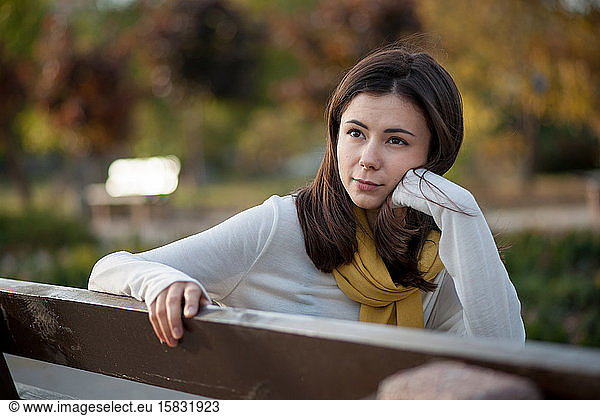 beautiful brunette girl resting in the autumn in the park on a b