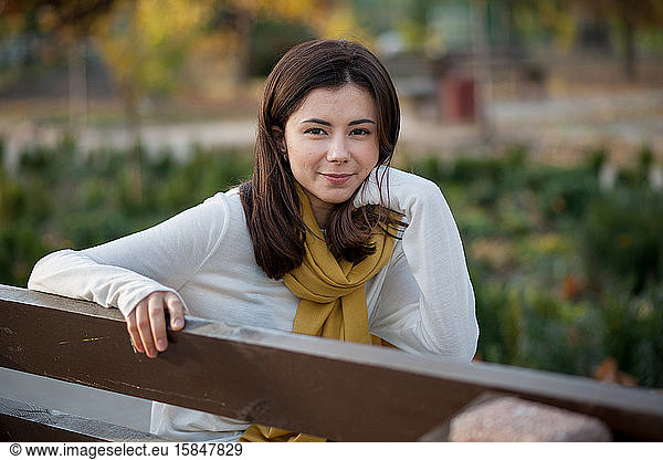 beautiful brunette girl resting in the autumn in the park on a b