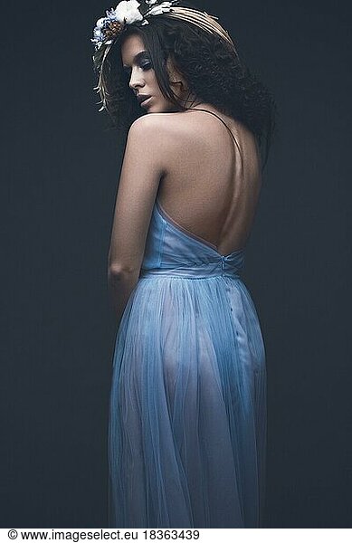 Beautiful girl in a light blue dress and long hair in a fashionable image. Beauty fashion style. Picture taken in the studio with mixed light