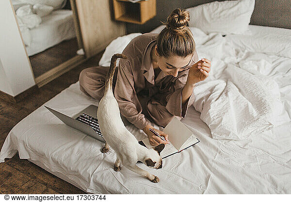 beautiful girl sitting on the bed with a laptop and studying
