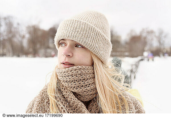Beautiful girl wearing knit hat looking away during winter