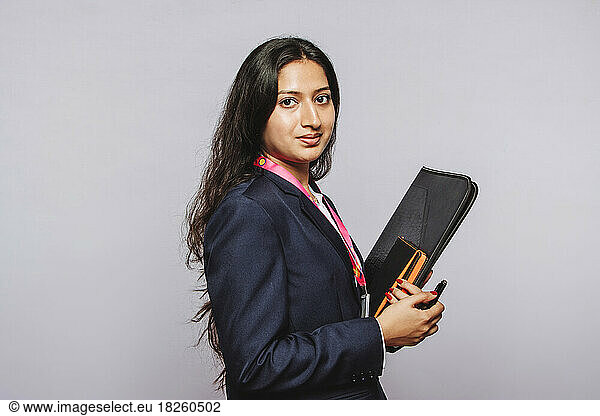 beautiful indian millennial girl holding book in grey background