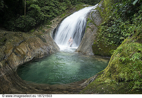 Beautiful landscape of man bathing on crystal clear blue waterfall