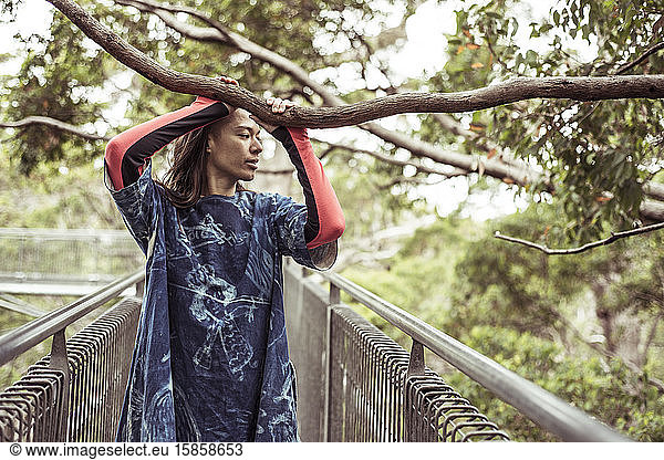Beautiful mixed race human holds branch on tree top walk in australia