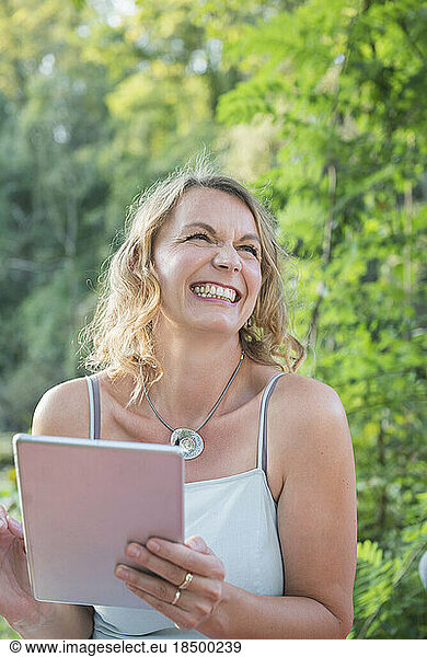 Beautiful smiling woman using digital tablet in nature  Germany